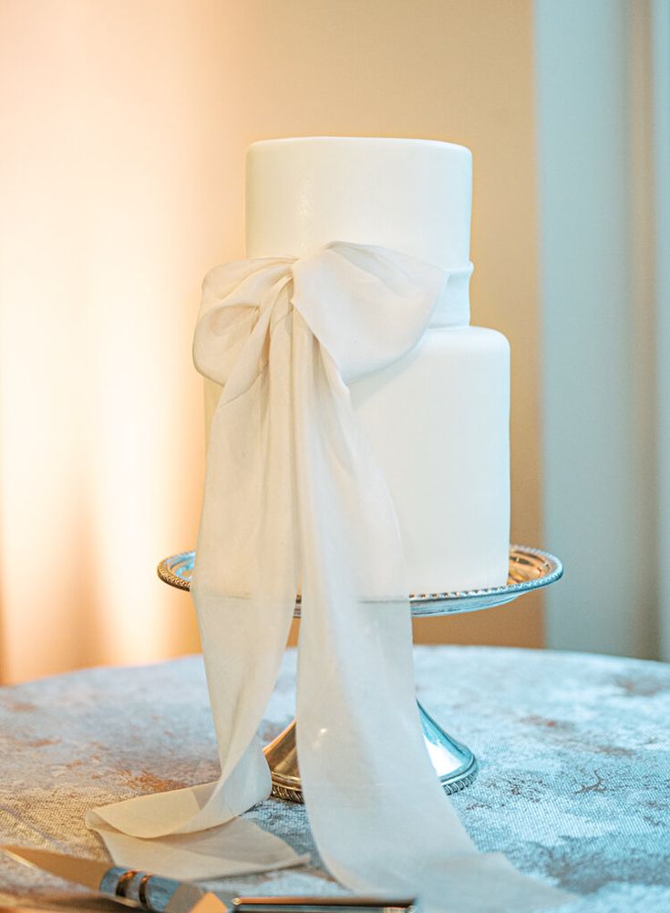 a white wedding cake sitting on top of a table next to a pair of scissors