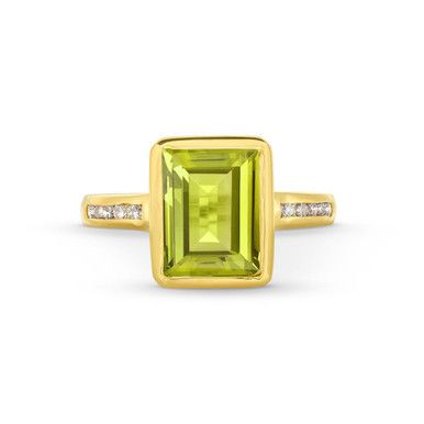 This Peridot Diamond Bezel Ring features an emerald cut peridot gemstone totaling approximately 3 carats, accented by a line of brilliant round diamonds on each side. Classic Green Emerald Ring With Gemstone Accents, Green Octagon Diamond Ring, Emerald Cut Green Gemstones With Accent Stones, Classic Green Gemstones With Accents, Green Diamond Ring With Gemstone Accents For May Birthstone, Fine Jewelry Green Diamond Ring With Gemstone Accents, Luxury Green Channel Set Rings, Classic Peridot Gemstone Diamond Ring, Green Peridot Diamond Ring With Accent Stones