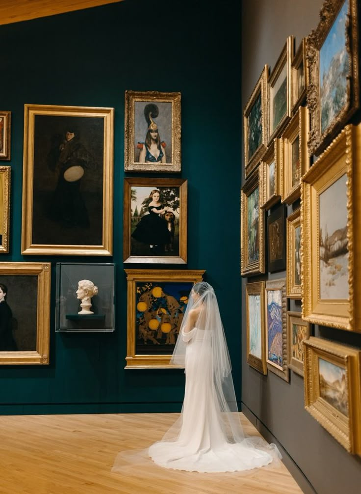 a bride standing in front of paintings on the wall