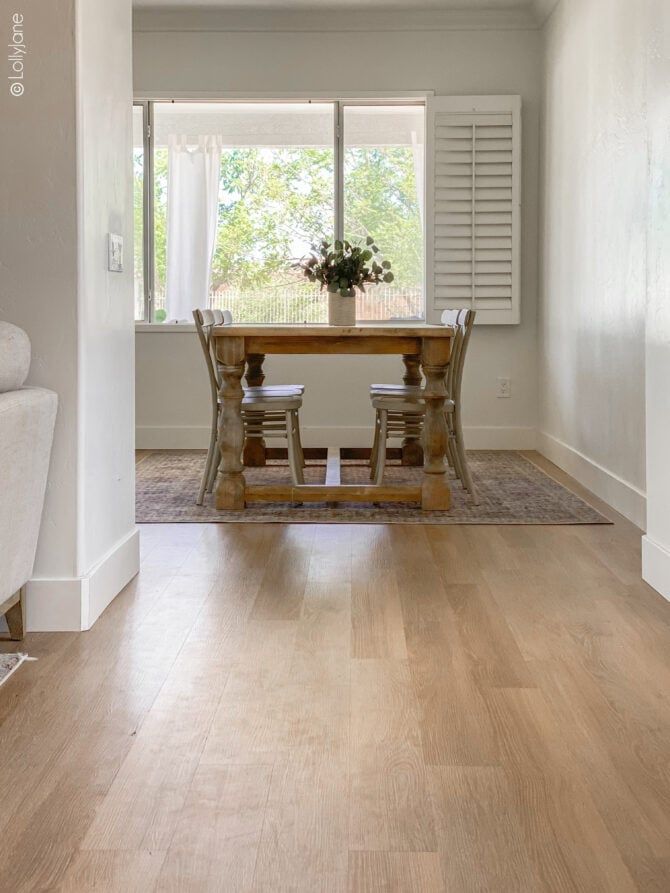 a dining room table and chairs in front of a window with shutters on both sides