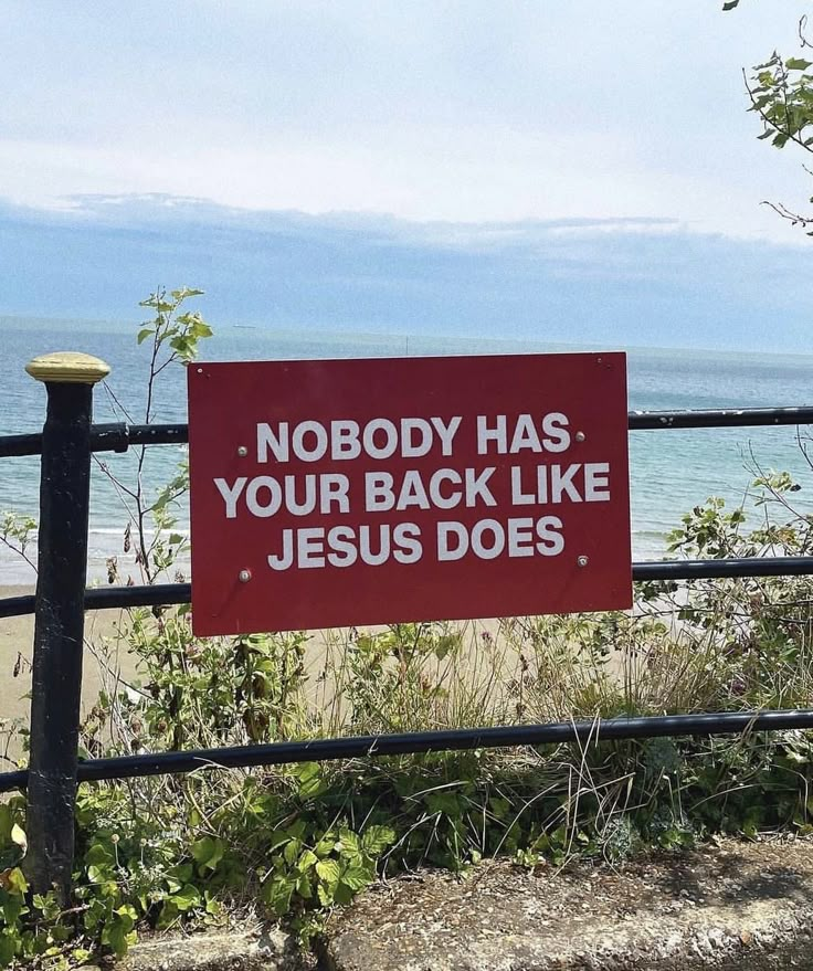 a red sign that says nobody has your back like jesus does next to a fence