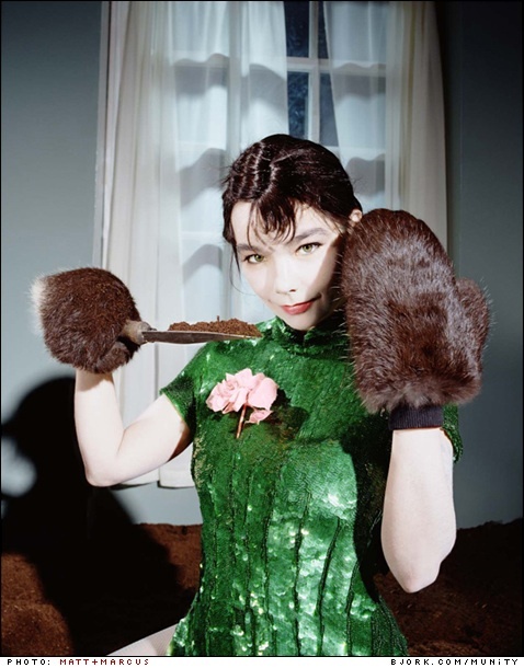 a woman in a green dress with fur gloves on her head and holding a knife