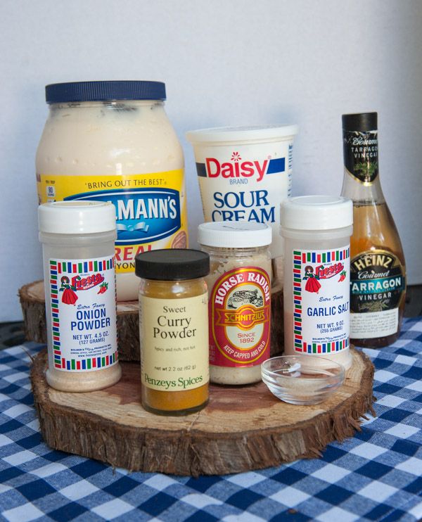 an assortment of condiments are displayed on a wood slice with a checkered tablecloth