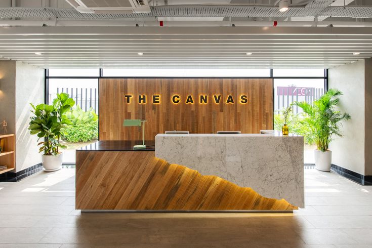 an office lobby with a marble reception desk and wooden sign that reads the canvass