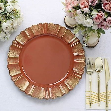 an orange plate sitting on top of a white table next to silverware and flowers