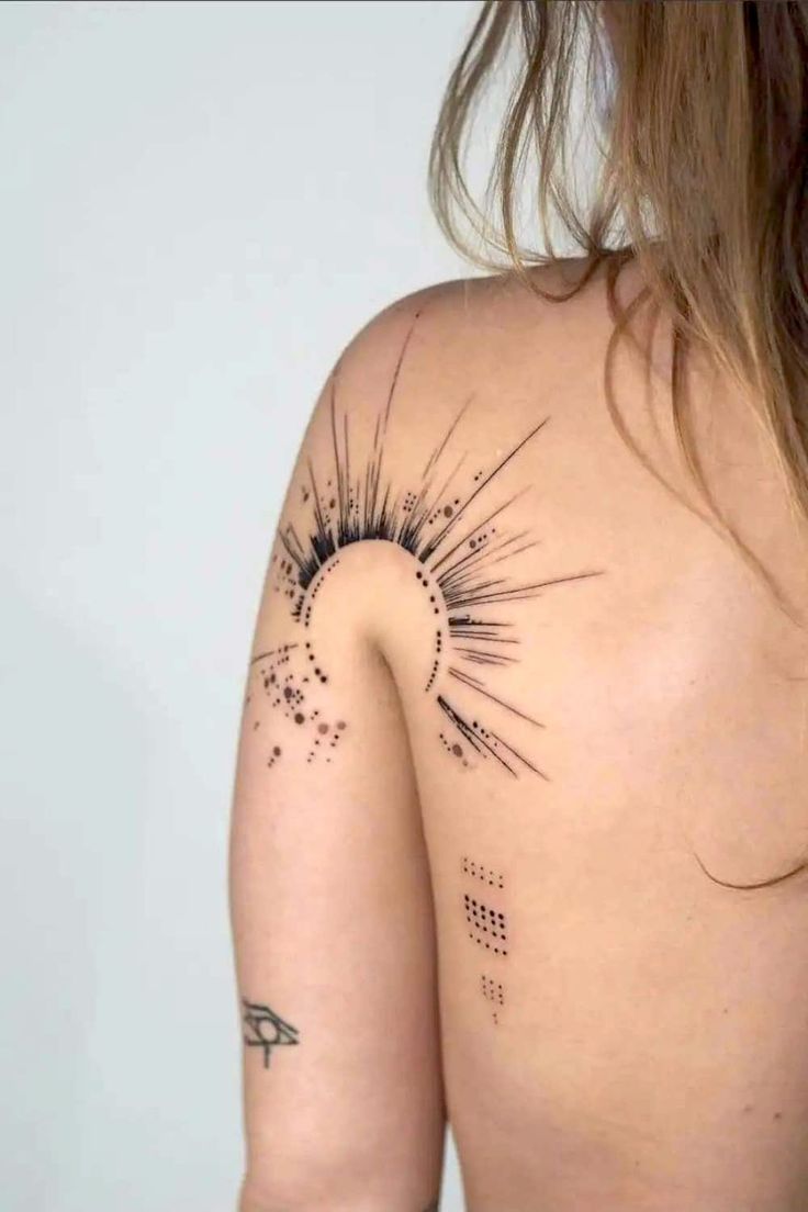 the back of a woman's shoulder with an abstract tattoo design on her left arm