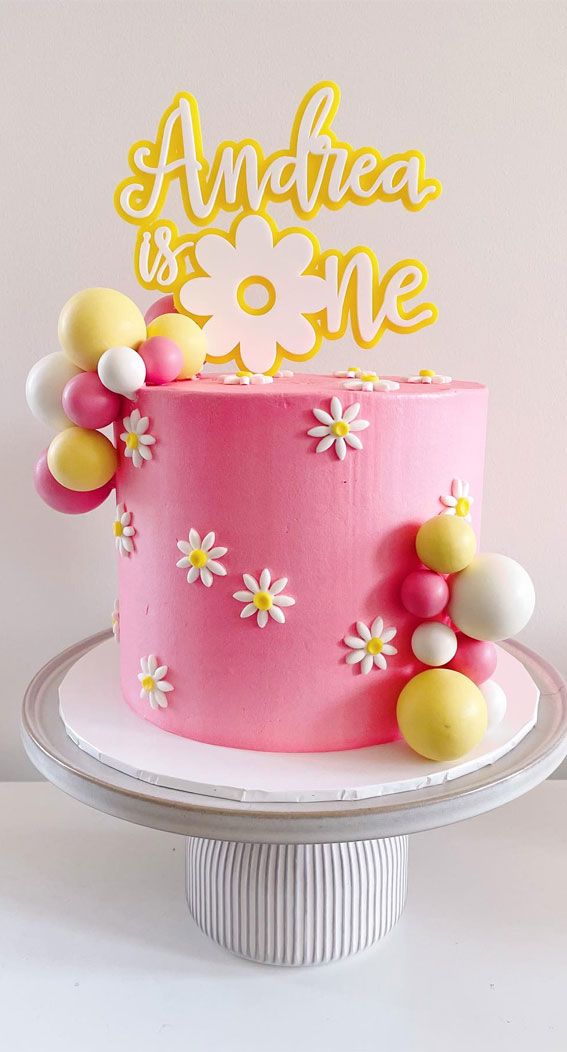 a pink cake with yellow and white decorations on top that says an idea is one