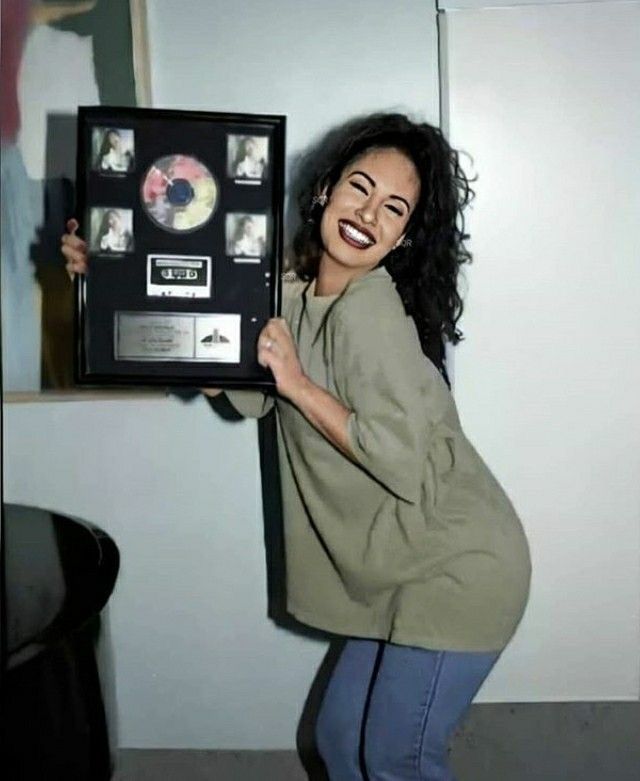 a smiling woman holding up a framed cd case with cds in it's sides