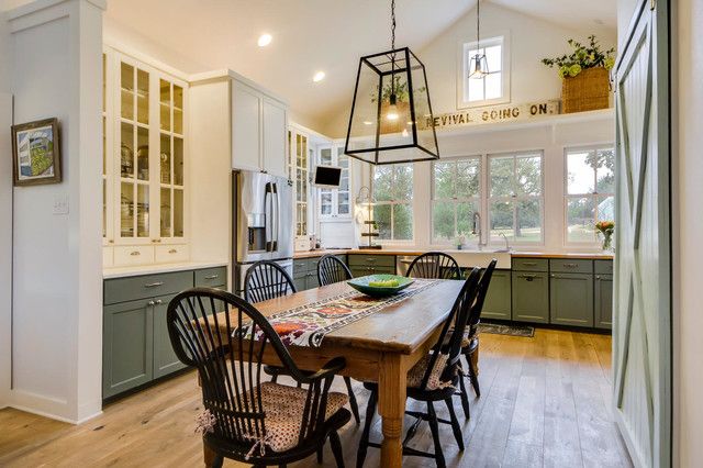 an open kitchen and dining room with wood floors, white walls, and green cabinets