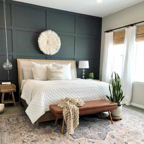 a bedroom with a bed, chair and potted plant on the floor in front of it