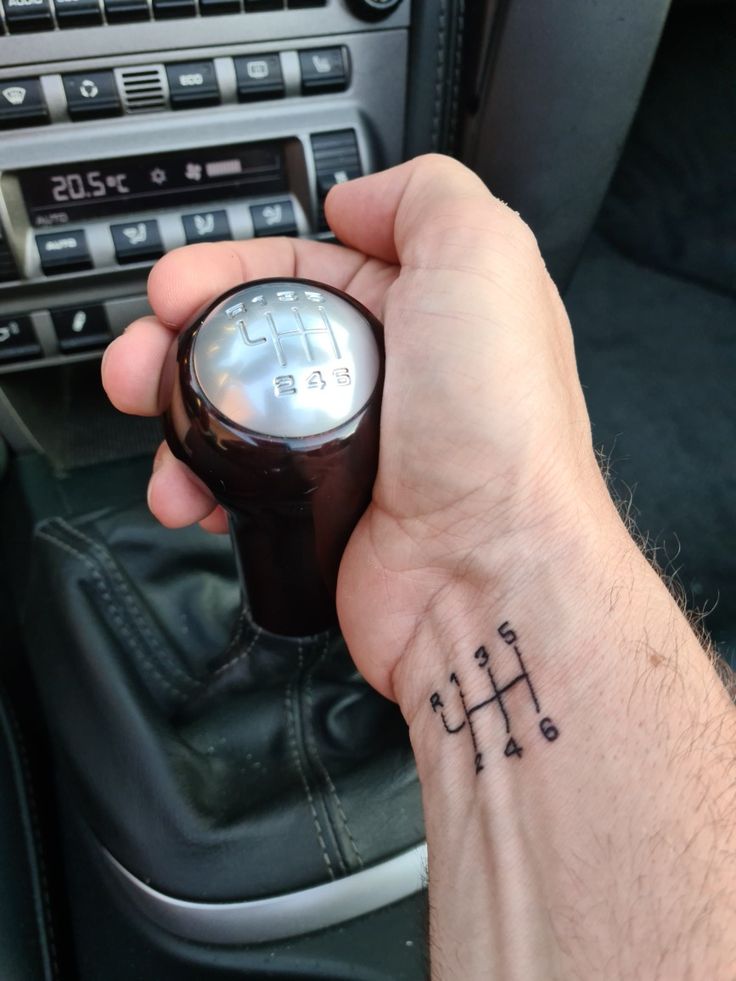 a man is holding a car gauge in his hand and has a small tattoo on the wrist