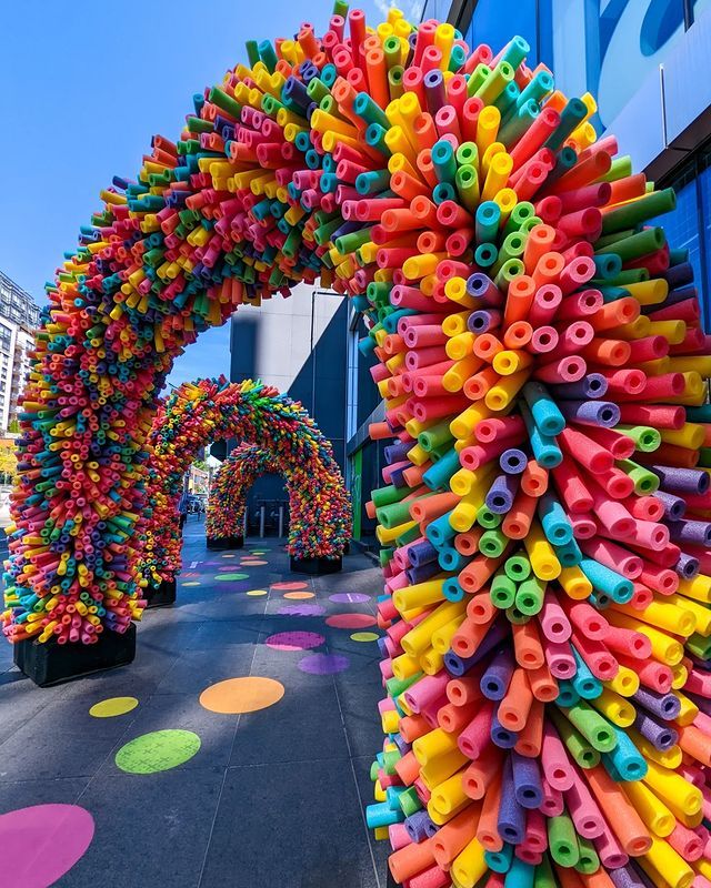 an arch made out of colored plastic tubes and sprinkles in front of a building