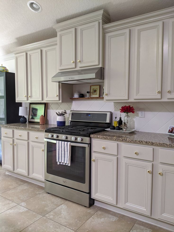 a kitchen with white cabinets and an oven in the center, has a towel hanging on the stove