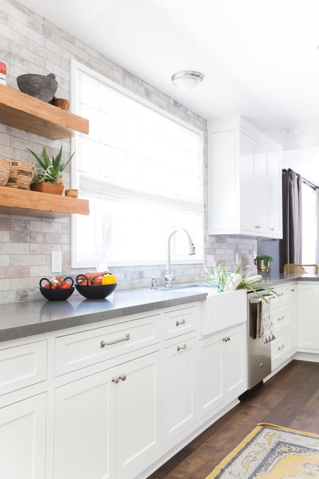 a kitchen with white cabinets and wooden shelves