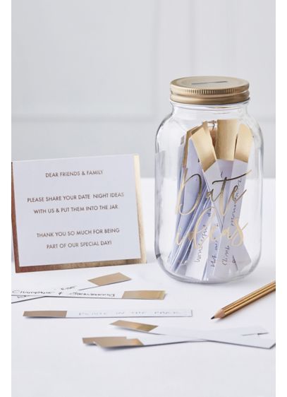 a jar filled with gold and silver items on top of a white table next to a card