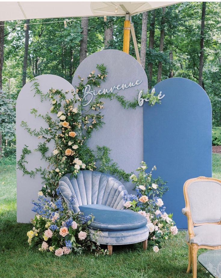 an outdoor seating area with flowers and greenery on the wall, next to two chairs