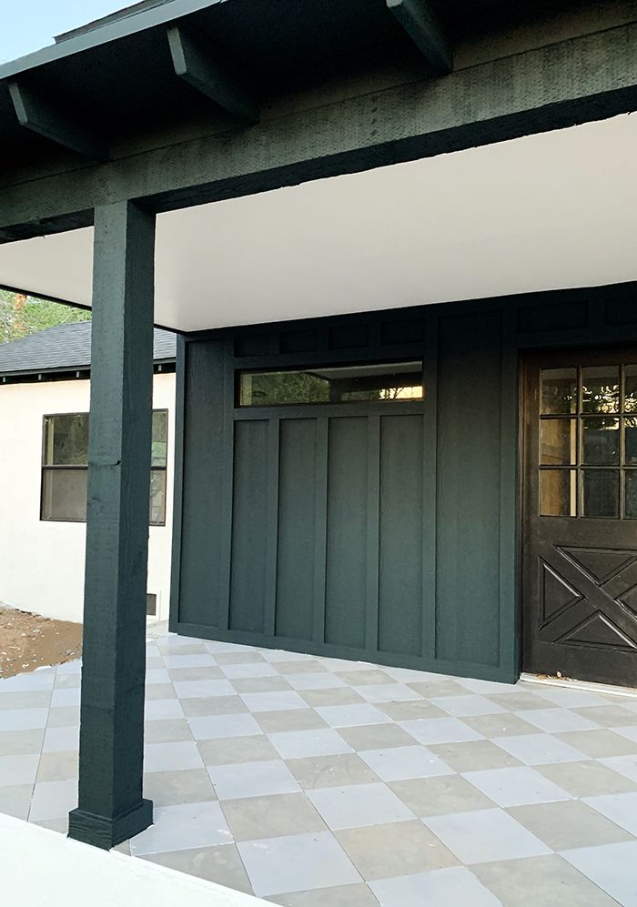 a black and white checkered tile floor in front of a house with an open door