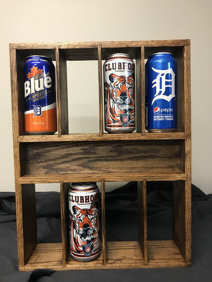 three cans of beer are sitting in a wooden shelf on a black cloth covered bed