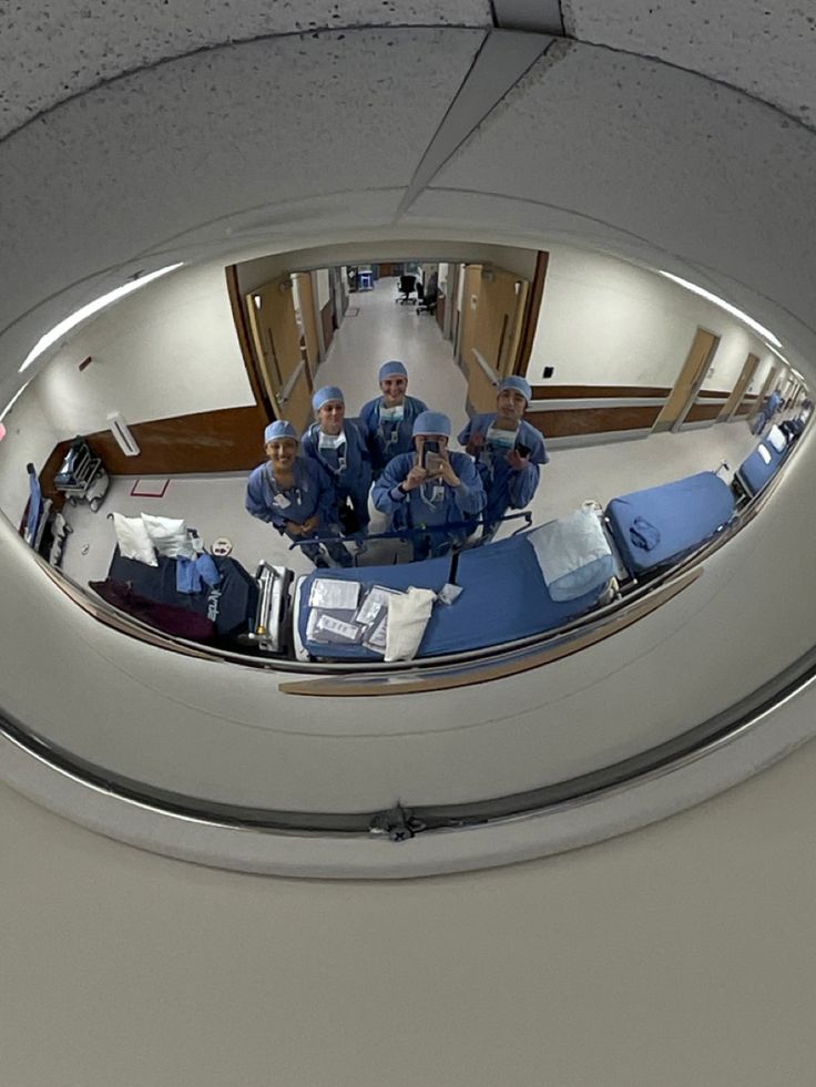 a group of doctors in scrubs sitting on top of a hospital bed looking at the camera