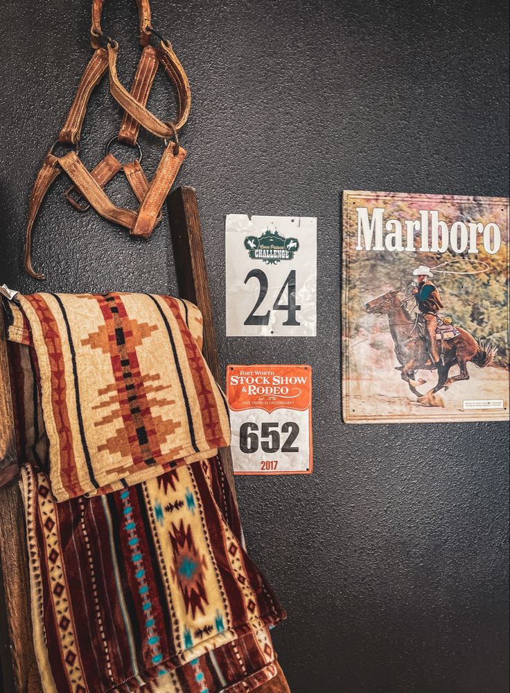 an old saddle hanging on the wall next to some posters