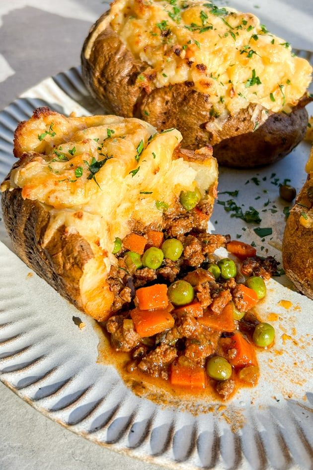 baked potatoes with meat and vegetables on a paper plate