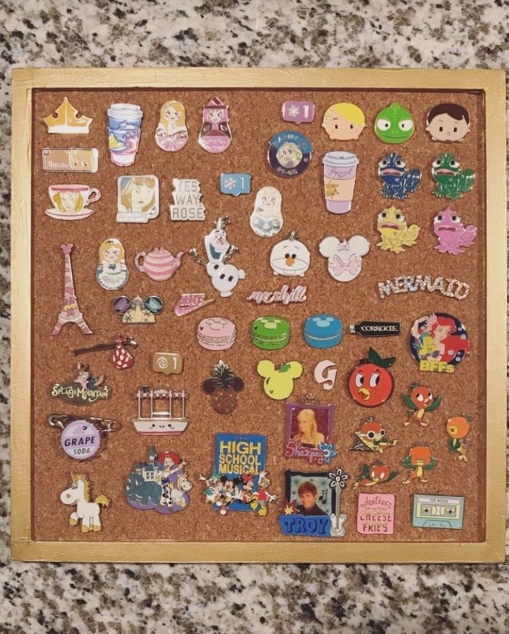 a cork board covered in lots of stickers on top of a counter next to a wall