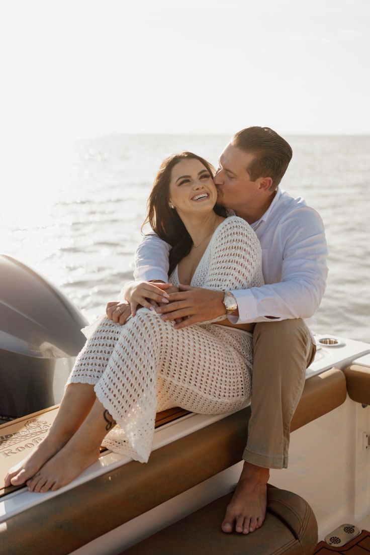 a man and woman are sitting on the back of a boat in front of the water