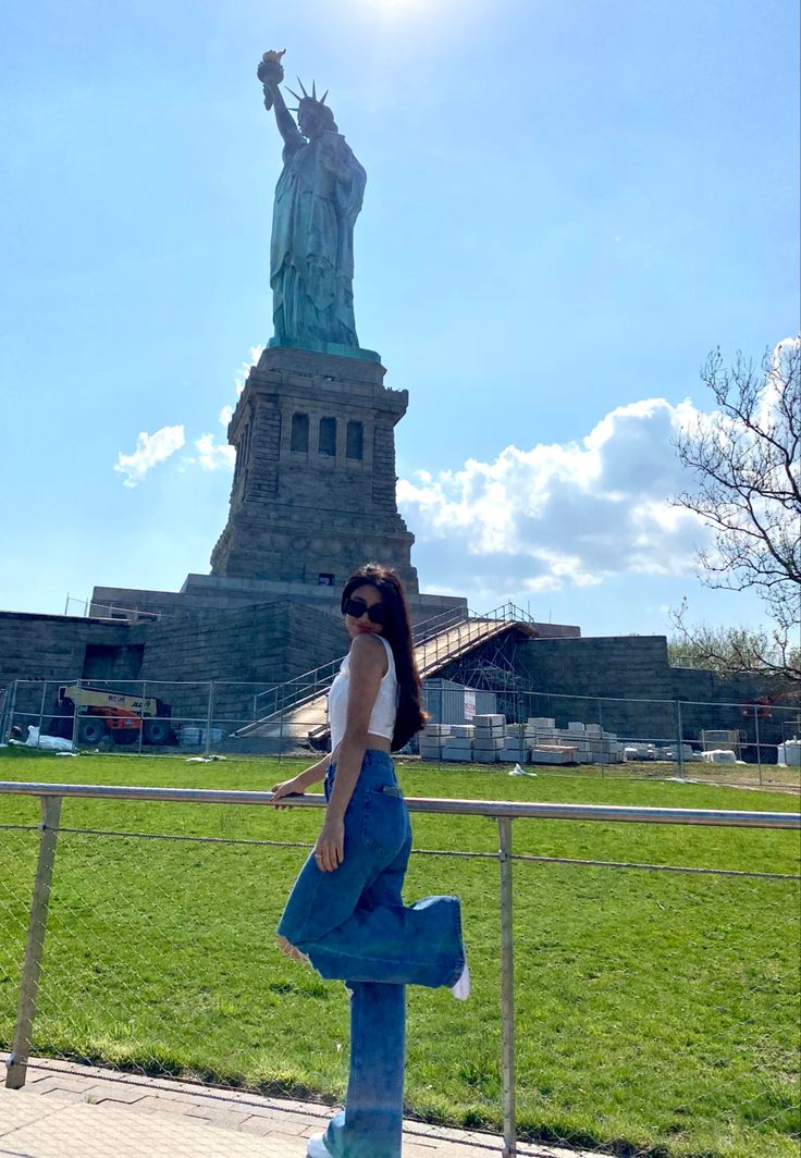 a woman standing in front of the statue of liberty