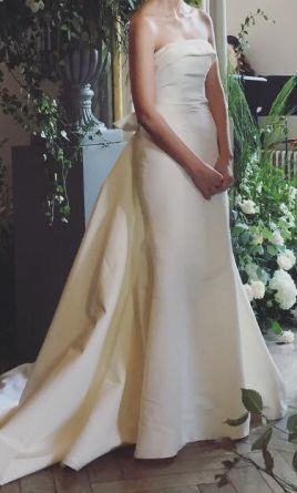 a woman in a wedding dress standing next to a flower arrangement and looking at the camera