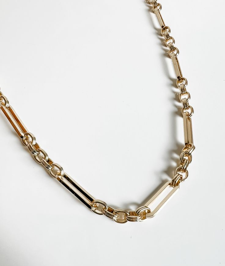 a gold chain with two different links attached to the link, on a white surface