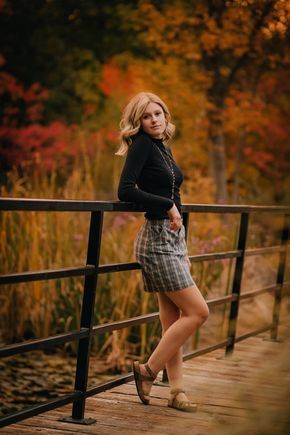 a woman standing on a bridge in front of trees