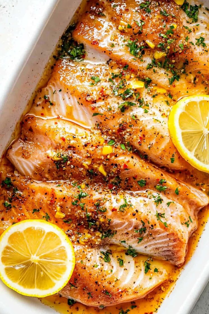 baked fish with lemons and herbs in a baking dish