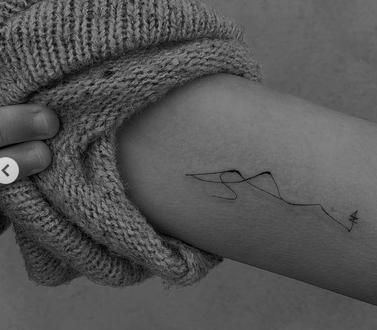 a woman's arm with a small wave tattoo on the left side of her arm