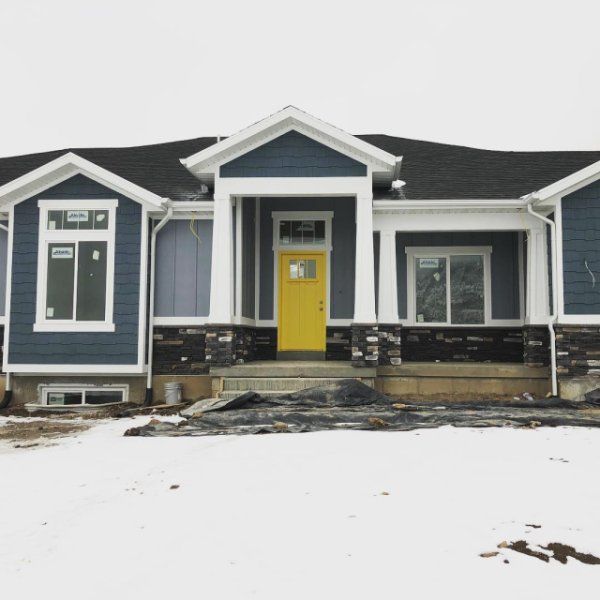 a house with snow on the ground in front of it and two garages behind it