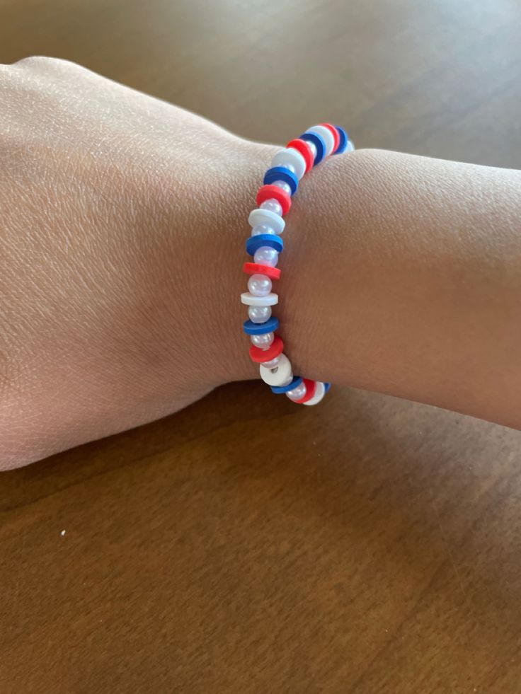 a person's hand with a red, white and blue beaded bracelet