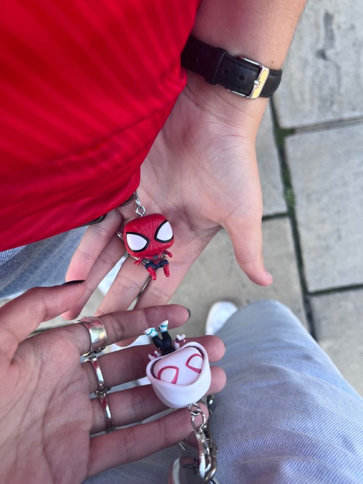 two people holding each other's hands with spiderman rings on them