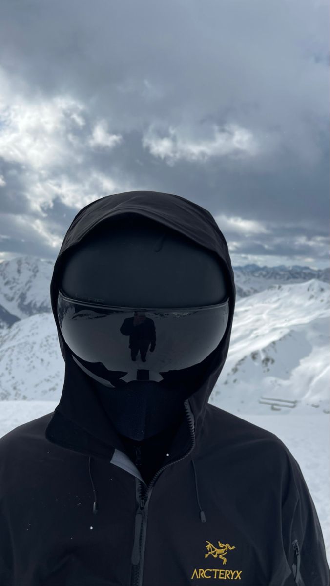 a man in black jacket standing on top of a snow covered slope