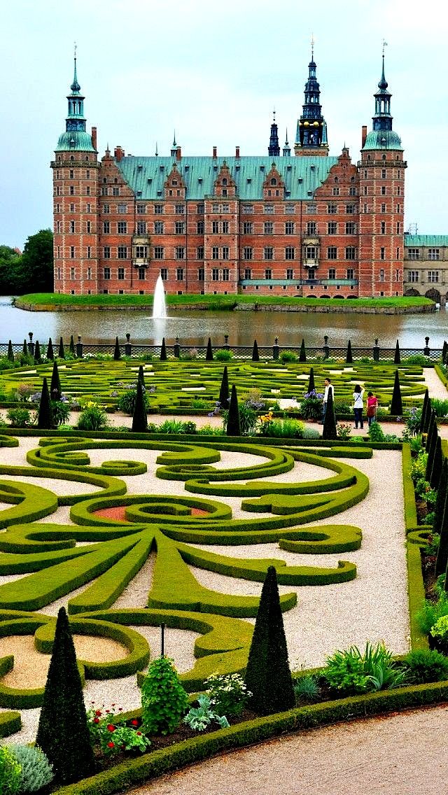 a large building with many hedges in front of it