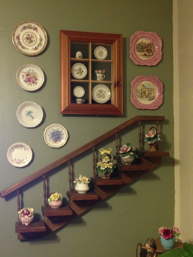 a staircase with plates on the wall next to it and a framed picture above it