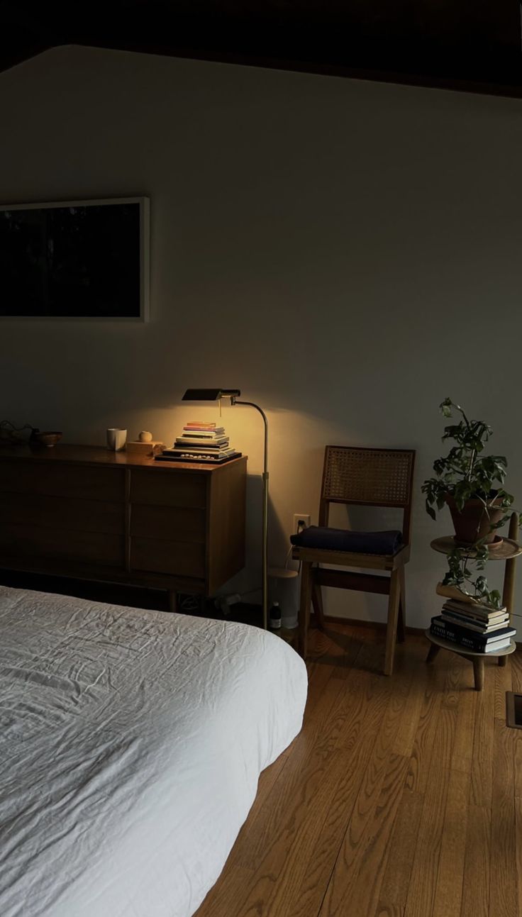 a bedroom with a bed, chair and lamp on the side table in front of it