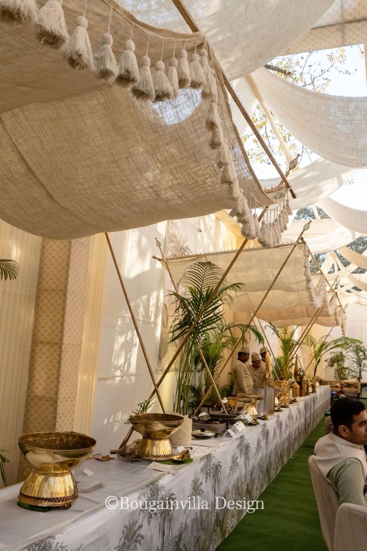 people are sitting at tables with white cloths on the ceiling and hanging decorations above them