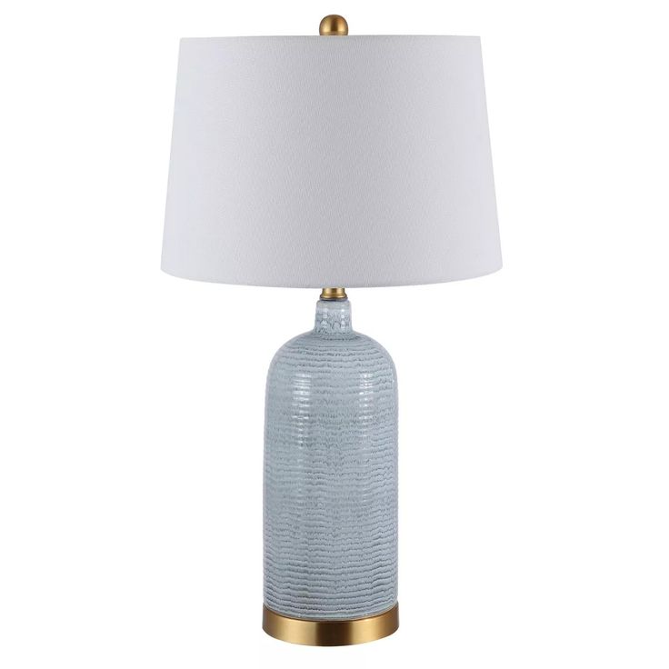 a blue glass table lamp with a white shade on the top and gold trim around the base