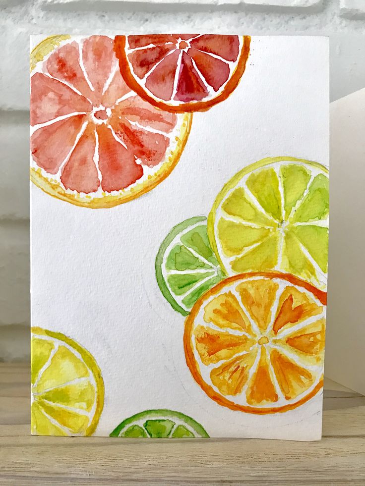 a card with watercolored citrus fruit slices on it, sitting on a table