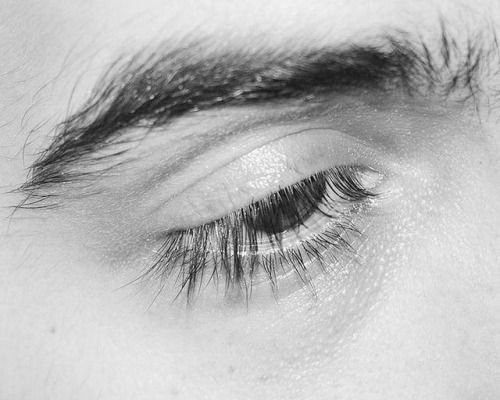 the eye of a person with long lashes and no makeup is seen in this black and white photo