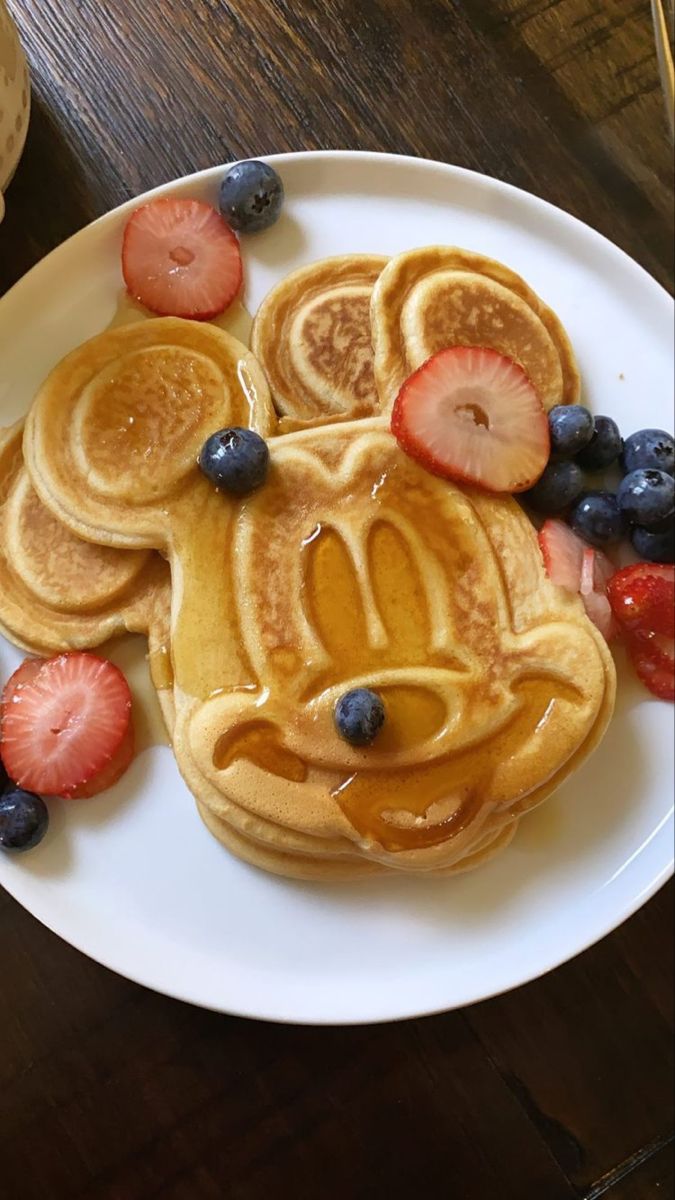 mickey mouse pancakes with strawberries and blueberries on a plate