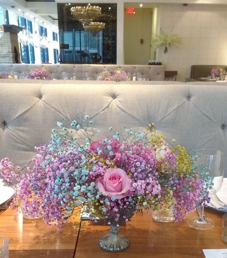 a vase filled with flowers sitting on top of a wooden table next to a white couch