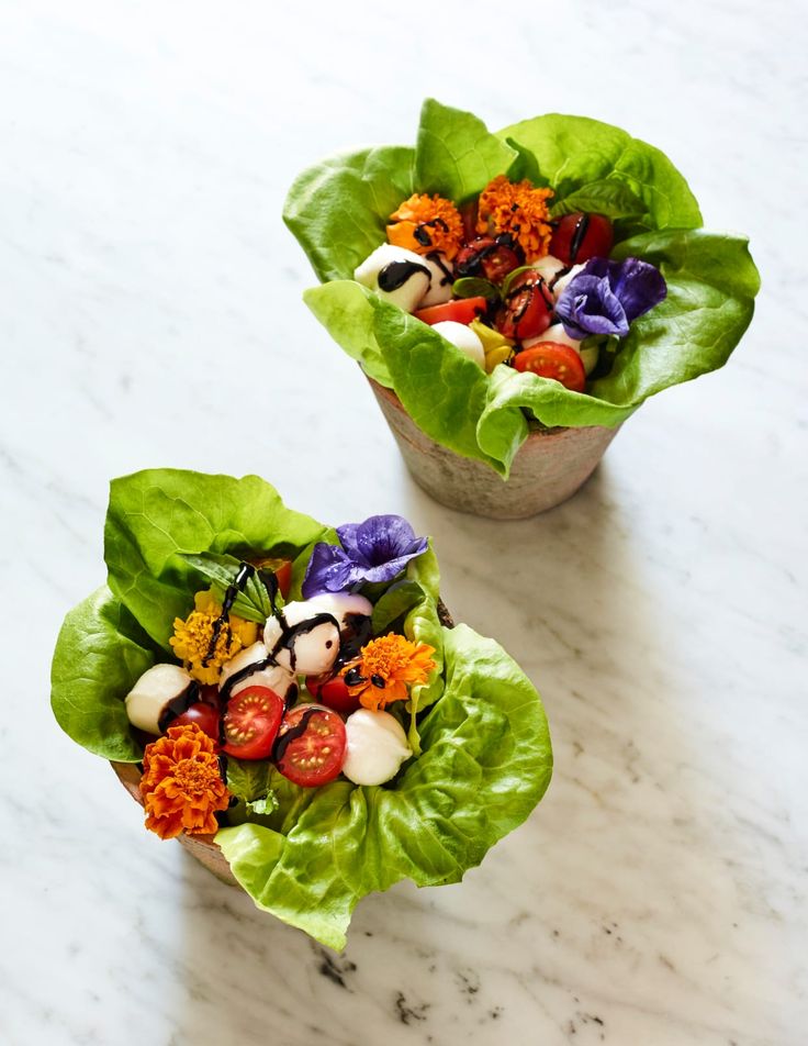 two lettuce cups filled with colorful vegetables on top of a marble countertop