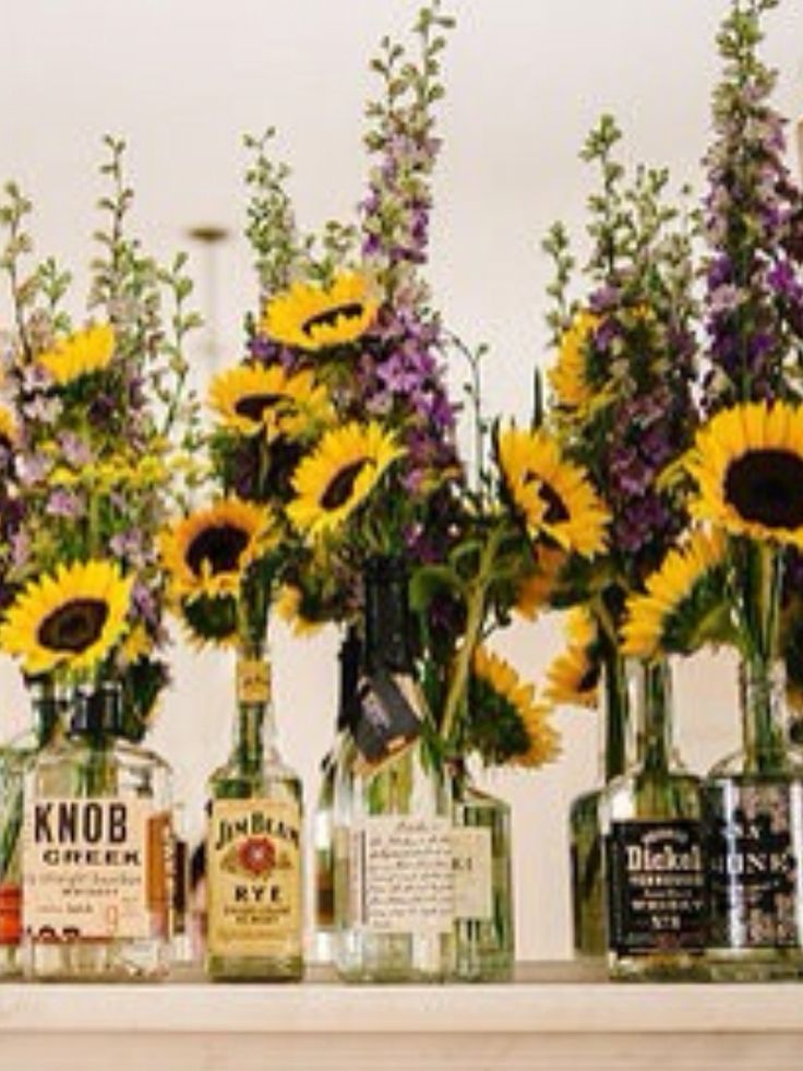 sunflowers and liquor bottles are arranged on a shelf