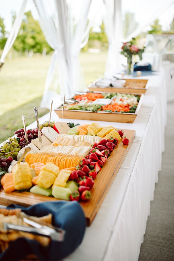 an assortment of fruits and cheeses on a buffet table at a wedding or event