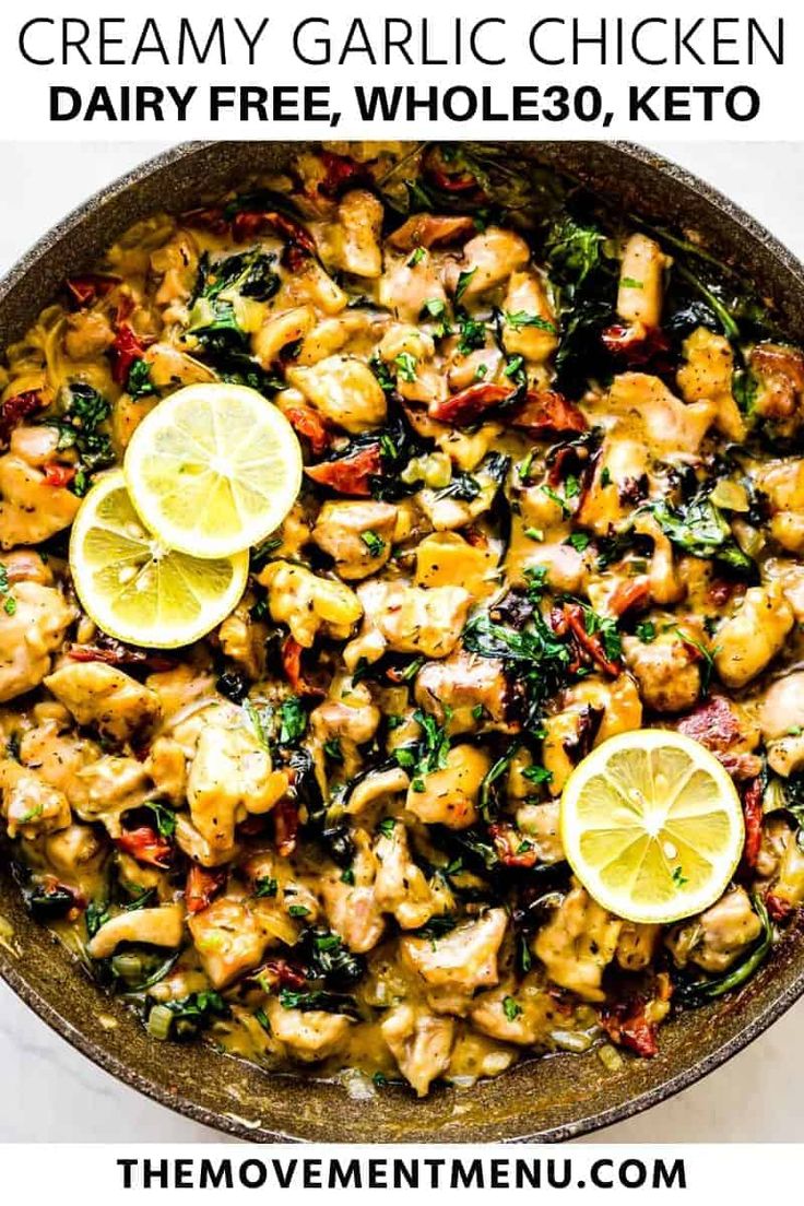 chicken and spinach stir fry in a skillet with lemons on the side